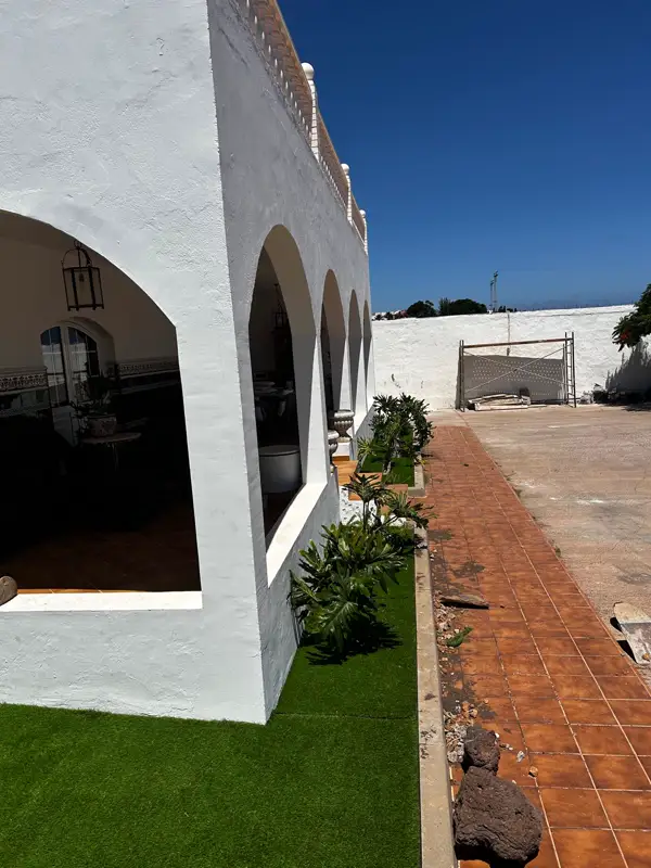 Franja de césped artificial junto al camino de baldosa y la casa con arcos en Carrizal