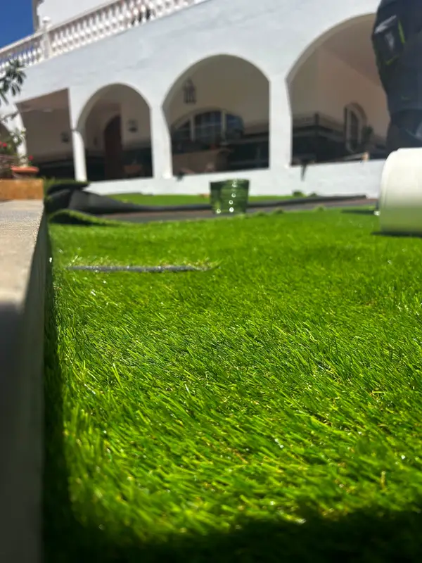Detalle de la fibra del césped artificial junto a la casa con arcos en Carrizal