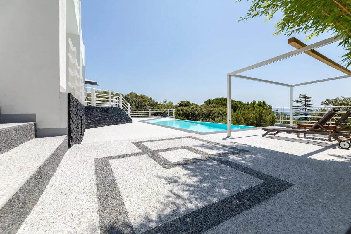 Terraza de piscina con pavimento drenante Résineo blanco y diseño geométrico a medida