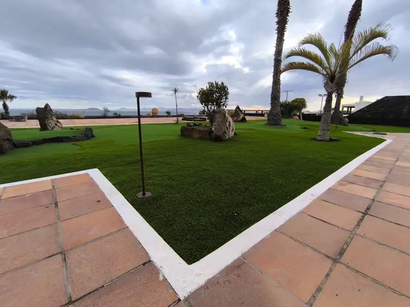Césped artificial junto a un paseo de baldosa frente al mar en Lanzarote
