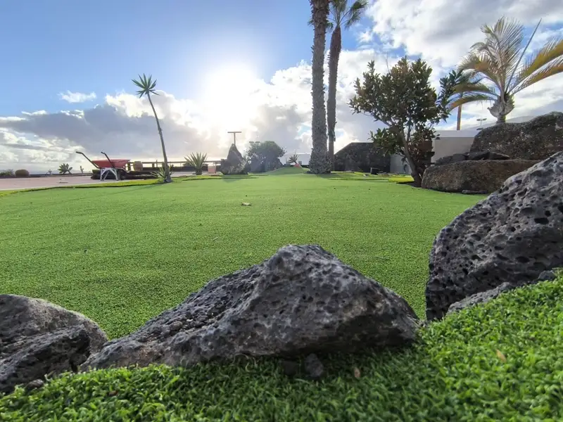 Césped artificial con roca volcánica en un paseo marítimo de Lanzarote