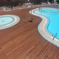 Zona p&iacute;scina con c&eacute;sped y tarima en complejo hotelero